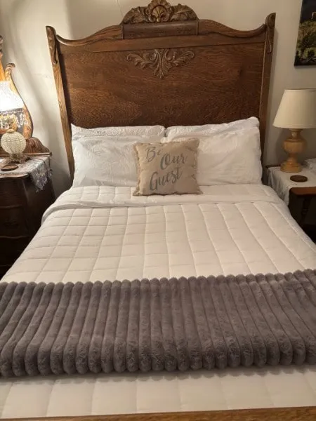 A carved wooden bed from the late 1880s, made up with white bedding, in one of the hotel's rooms